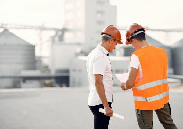 Engineers near the factory. Mtn in a helmet. Inspector looks at the building.